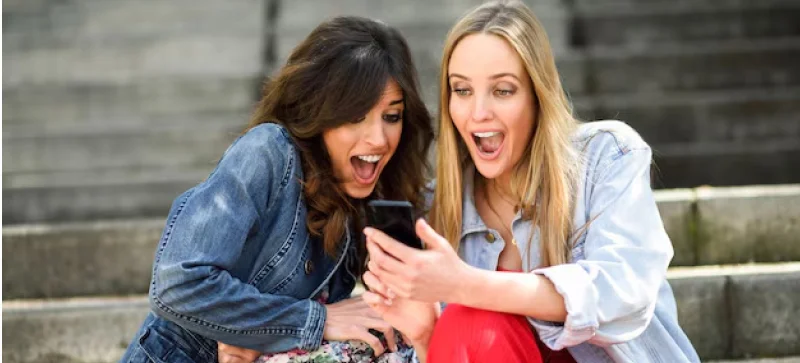 two girls checking phone looking excited